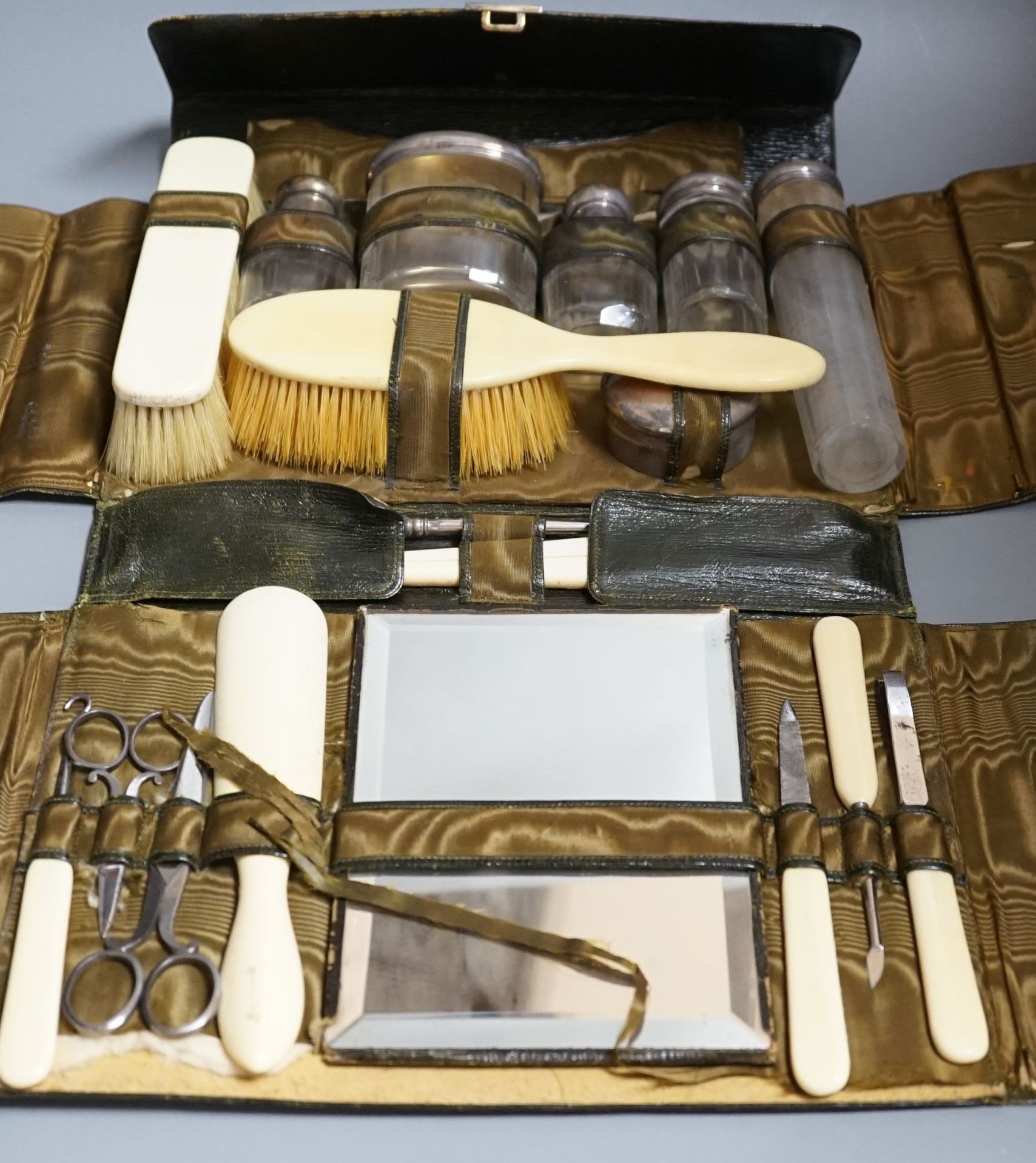 A George V J.C. Vickery leather travelling vanity case, containing five silver mounted toilet jars, silver box and twelve other accoutrements, London, 1910, case 29cm.